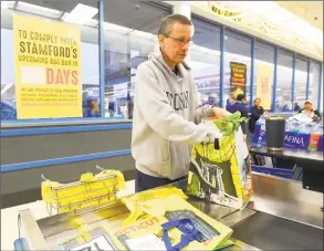  ?? Matthew Brown / Hearst Connecticu­t Media ?? Nick D'Alessan, of Stamford, bags his own groceries using recyclable bags after shopping at ShopRite in April in Stamford.