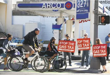  ?? Paul Chinn / The Chronicle ?? Barry Graynor (left), Howard Epstein and Lisa Remmer protest the new gas-tax increase at Fell and Divisadero streets in S.F.