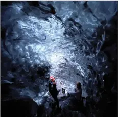 ?? (AP/Beth Harpaz) ?? Visitors inspect an ice cave at Vatnajokul­l National Park, located on an ice field in southeaste­rn Iceland. The caves can only be explored on a tour with a registered guide. Winter crampons must be attached to shoes and boots for traction to avoid slipping.