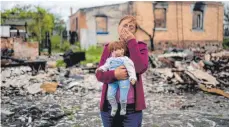  ?? FOTO: NATACHA PISARENKO/DPA ?? Spuren des Krieges: Eine Frau hält vor einem zerstörten Haus in der Nähe von Kiew eine Puppe ihrer Enkelin in der Hand.