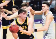  ?? Nam Y. Huh / Associated Press ?? Iowa center Luka Garza (55) looks to pass against Northweste­rn forward Pete Nance, right, and center Ryan Young on Sunday. Garza put up 17 points and 10 rebounds in 24 minutes of play.