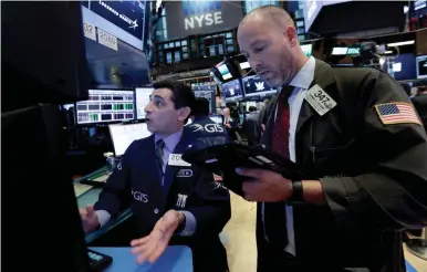  ?? AP ?? Specialist Peter Mazza, left, and trader Thomas Cicciari work on the floor of the New York Stock Exchange on Monday. The markets ended the day mixed.