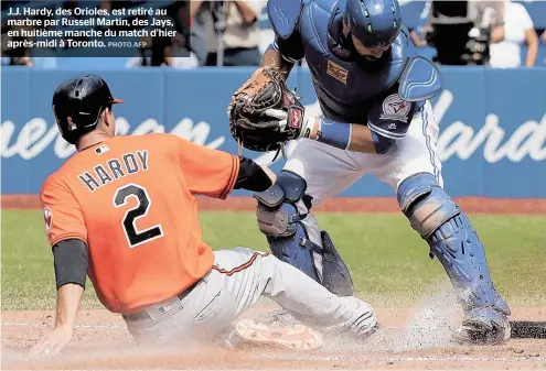  ??  ?? J.J. Hardy, des Orioles, est retiré au marbre par Russell Martin, des Jays, en huitième manche du match d’hier après-midi à Toronto.