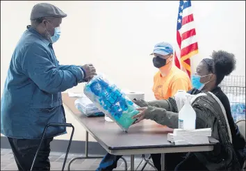  ?? KYLE TELECHAN/POST-TRIBUNE ?? Student worker Cierra Williams, right, hands out personal protective equipment and sanitizati­on supplies to an election inspector Saturday.