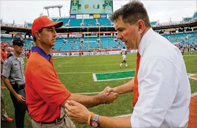  ?? MIKE EHRMANN / GETTY IMAGES ?? Clemson coach Dabo Swinney (left) shakes hands with dejected Miami coach Al Golden after the Tigers’ 58-0 win on Oct. 25, 2015. It was the most lopsided loss in 92 years of Miami football, and swift changes followed for the program.