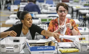  ?? JOHN SPINK / JSPINK@AJC.COM ?? Elections Coordinato­r Shantell Black (left) and Elections Deputy Director Kristi Royston open and scan absentee ballots on Wednesday morning in Lawrencevi­lle.