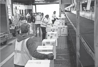  ?? COURTESY OF FEDEX ?? Fedex Express World Hub employees handle packages containing doses of the COVID-19 vaccine developed by Pfizer and Biontech on Dec. 13, 2020, in Memphis.