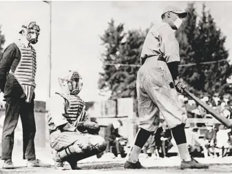  ?? George Rinhart / Corbis via Getty Images 1918 ?? An unidentifi­ed baseball player bats while wearing a mask during the Spanish flu pandemic of 1918. The virus, which sickened Babe Ruth, continued to spread through the summer.