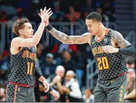  ?? CURTIS COMPTON / CCOMPTON@AJC.COM ?? Trae Young (11), who had 36 points and 10 assists, and John Collins, who added 22 points and 10 rebounds, high-five during Tuesday’s win against the Suns.