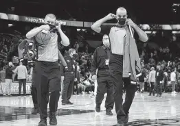  ?? Phelan M. Ebenhack / Associated Press ?? Officials Tyler Ford, left, and Matt Myers wear face masks to help curb the spread of COVID-19 while leaving after a game between the Magic and Hornets.