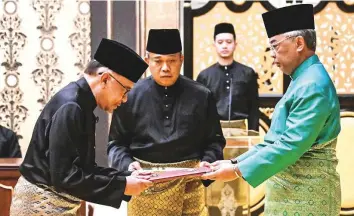  ?? AP ?? King Sultan Abdullah Sultan Ahmad Shah, right, and Anwar Ibrahim take part in the swearing-in ceremony at the National Palace in Kuala Lumpur, Malaysia, yesterday.