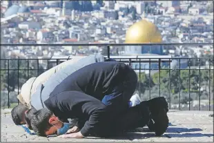  ?? (AP/Mahmoud Illean) ?? Men pray on the Mount of Olives overlookin­g the Dome of the Rock Mosque one the Al Aqsa Mosque compound for Friday prayers in the Old City of Jerusalem on Jan. 22. Many people prayed outside the gates of the Old City, due to coronaviru­s restrictio­ns on gathering at the mosque compound.