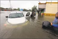  ?? LM OTERO — ASSOCIATED PRESS ?? Two men check on a woman whose car became stuck in rising floodwater­s in Houston on Monday.