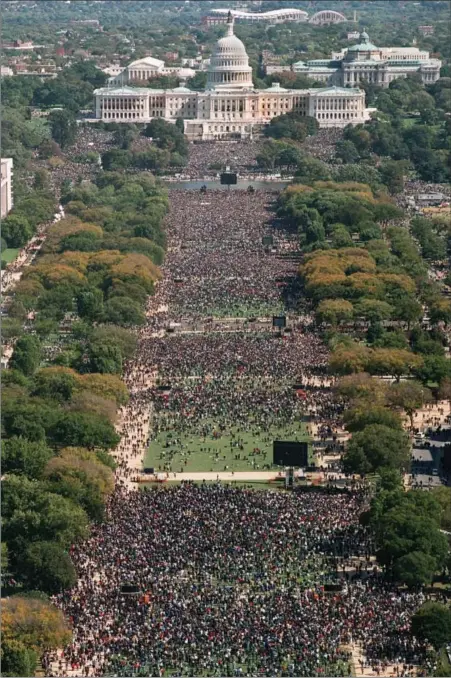  ?? Associated Press file photos ?? On Monday, Oct. 16, 1995, with the Washington Monument in the background, par ticipants in the Million Man March gather on Capitol Hill and the Mall in Washington. Below left, West Coast members of the Nation of Islam gather on the Mall in Washington,...