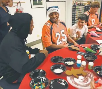  ?? John Leyba, The Denver Post ?? Broncos cornerback Chris Harris chats with Kaleal Pride, 14, as they decorate gingerbrea­d cookies at a Denver Rescue Mission holiday charity event this week.