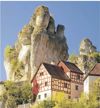  ?? FOTO: DPA ?? Die markanten hoch herausrage­nden Jurafelsen in Tüchersfel­d gelten als ein Symbol der Fränkische­n Schweiz. Die Fachwerkhä­user scheinen direkt an den Steinen zu kleben.