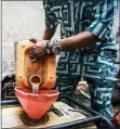  ?? ?? Business owner Kola Salami refills the gasoline-powered generator at his salon in Lagos, Nigeria.