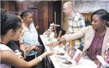  ?? (Photos: Garfield Robinson) ?? Rennae Johnson (right) and her husband Wouter Tjeertes giving samples of their chocolates to members of the public who attended the recent “Christmas in July” expo at the Jamaica Pegasus hotel.
