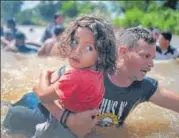  ?? REUTERS ?? A file photo of a migrant from Honduras holding his daughter while crossing the Suchiate River into Mexico from Guatemala.