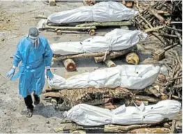  ?? Picture: REUTERS / ADNAN ABIDI ?? HEAVY TOLL: A health worker walks past a row of bodies of Covid-19 victims waiting to be cremated in New Delhi, India.