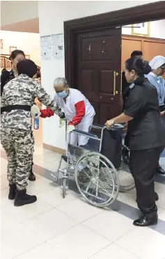  ??  ?? Prison officers help Naphaporn to get into her wheelchair outside the court room after the hearing.