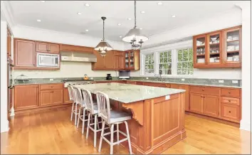  ??  ?? The kitchen was designed with functional­ity in mind, with a large center island and lots of room to move around it. Lightly finished cheery cabinets are complement­ed by the light-green granite surfaces and stainless appliances. Plus, there’s a butler’s pantry with additional storage and work space.