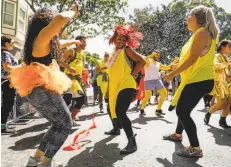  ??  ?? Kimiko Mitchell (center) dances with friends as they make their way through the race. Tens of thousands of people participat­ed.