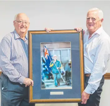  ??  ?? TRUE COLOURS: Retiring ECU Australia board member Clive Skarott (left) was presented with a framed photograph of himself carrying the flag for Australia at the 2008 World Credit Union Conference. New ECU director and deputy chairman John Gilbert made...