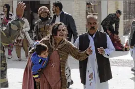  ?? ARSHAD BUTT / ASSOCIATED PRESS ?? A man helps an injured woman and a child following an attack on a church in Quetta, Pakistan, on Sunday. Two suicide bombers attacked the church when hundreds of worshipers were attending services ahead of Christmas.