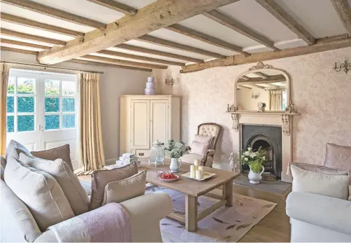  ??  ?? Living room
The neutral palette is punctuated with pale pink and heather accents.
Wallpaper, rug, Laura Ashley.
Sofas, Sofa Gallery.
Cupboard, made by a local carpenter.
Mirror, chair, Jojoõs Interiors.