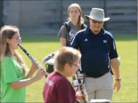  ?? JONATHAN TRESSLER — THE NEWS-HERALD ?? Fairport Skipper Marching Band director Chris Ruzin smiles as he interacts with students behind Fairport Harding High/Middle School during band class Oct. 5.