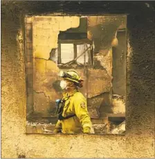  ?? Mason Trinca For The Times ?? A LEGISLATOR hopes to close a hole in a law to allow state utilities more flexibilit­y to cover costs associated with wildfires. Above, a Cal Fire crew member walks in a house in Paradise on Nov. 10.