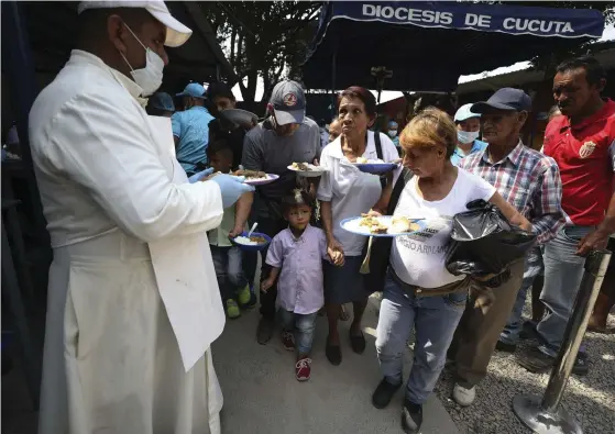  ?? FOTO: TT-AP/FERNANDO VERGARA ?? En präst vid en katolsk kyrka delar ut mat till venezuelan­ska migranter i La Parada, nära Cúcuta, Colombia.