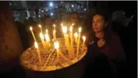  ?? MAJDI MOHAMMED/THE ASSOCIATED PRESS FILE PHOTO ?? A Christian worshipper lights a candle at the Church of the Nativity, where Christians believe Jesus Christ was born.