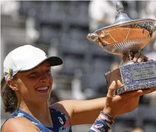  ?? ALESSANDRA TARANTINO / AP ?? Poland’s
Iga Swiatek has her cap adorned with an Ukrainian flag as she holds up the trophy after winning the final against Turkey’s Ons Jabeur at the Italian Open in Rome on Sunday. It was her fifth consecutiv­e tournament win.