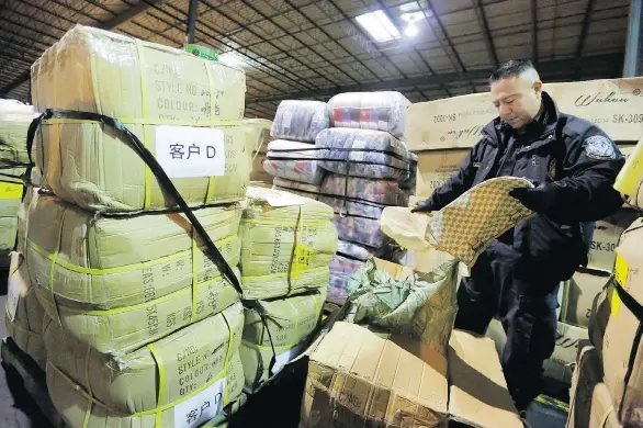  ?? RICHARD DREW/AP FILES ?? A U.S. border officer opens a shipment of counterfei­t Louis Vuitton bags in Kearny, N.J. The United States-Mexico-Canada Agreement requires all three countries to authorize their border guards to detain “ex-officio” — without a court order — pirated goods in transit to other nations. Canada is seen as a major in-transit point for such shipments.