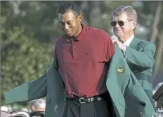  ?? Doug Mills/Associated Press ?? Tiger Woods receives the 2002 Masters Green Jacket from William W."Hootie" Johnson.