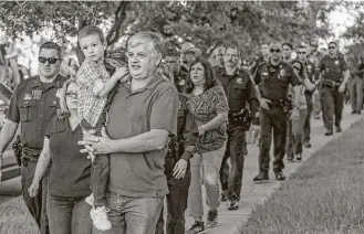  ?? Michael Ciaglo / Houston Chronicle ?? Kevin Will Jr. is carried by his grandfathe­r, Bernard Herring, and escorted to school by police Tuesday in Tomball. The boy’s father, HPD officer Kevin Will, was killed by a drunken driver.