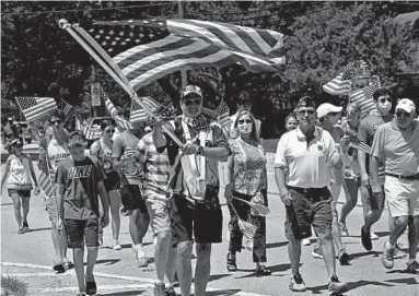  ?? JOE LEWNARD/AP ?? Veteran Matt Jaeger carries the American flag Saturday during an impromptu Fourth of July parade in Northbrook, Illinois.