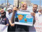  ?? NASSER SHIYOUKHI/ASSOCIATED PRESS ?? A Palestinia­n man holds a collage showing U.S. President Donald Trump during a protest against the visiting U.S. delegation in the West Bank city of Ramallah Thursday.