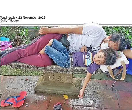  ?? PHOTOGRAPH BY JOEY SANCHEZ MENDOZA FOR THE DAILY TRIBUNE ?? DEAD tired after strolling Luneta Park Tuesday, a father and his son fall asleep on the sidewalk, unmindful of passersby.