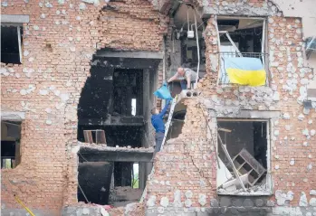  ?? EFREM LUKATSKY/AP ?? Residents take out belongings Saturday from their home ruined by shelling in Irpin, close to Kyiv, Ukraine.