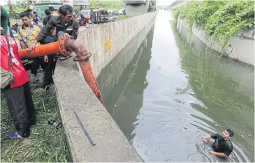  ??  ?? UP TO HIS ELBOWS: A city worker stands in water that has flooded a road underneath an expressway in Bang Phlat district of Bangkok. The district office said water pumps that were supposed to drain the area were not working because parts of the equipment had been stolen.