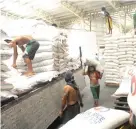  ?? AFP ?? WORKERS unload sacks of rice at a warehouse of the National Food Authority (NFA) in suburban Manila on October 7, 4014.