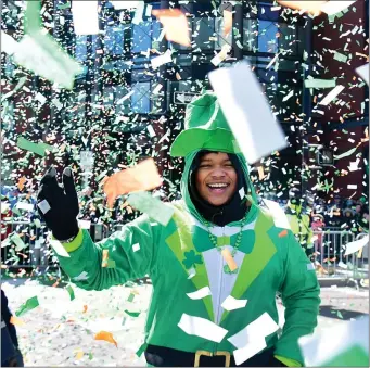  ?? PHOTOS BY JIM MICHAUD — BOSTON HERALD ?? Xavier Rodgers of Somerville, finds himself in a confetti storm, as the strong wind below the paper storm blows in the opposite direction it was intended as people celebrate St Patrick’s Day along Broadway in South Boston, Sunday.