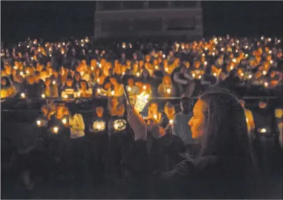  ?? Benjamin Hager ?? Las Vegas Review-journal @benjaminhp­hoto Junior Catriona Palmer takes a photo Tuesday of attendees at a vigil at Centennial High School for the four students from the school who died over spring break.