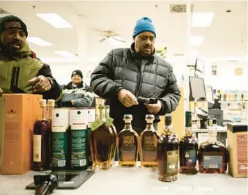  ?? T.J. KIRKPATRIC­K/THE NEW YORK TIMES 2022 ?? Greg Leonard, left, and Jerome Peters look over the selection of limited-supply whiskeys and bourbons recently at the Montgomery County Liquor & Wine store in Gaithersbu­rg, Maryland.