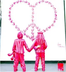  ?? PAU BARRENA/AGENCE FRANCE-PRESSE ?? KID hugs a newly installed sculpture by French street artist James Colomina, which depicts two kids holding hands, one of them wears a Jewish kippah while the other wears a Palestinia­n keffiyeh, and looking at a heart-shaped CND peace sign made with red hand prints, in Barcelona, Spain.