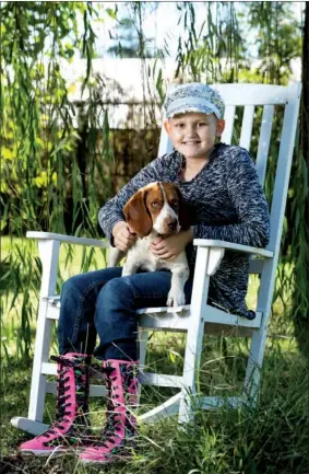  ?? NICK HILLEMANN/RIVER VALLEY & OZARK EDITION ?? Maddie Windle, 10, holds her dog Hazel in her lap at her home in Aplin near Perryville. Maddie was diagnosed with Wilms’ tumor, a type of kidney cancer, two years ago. Despite the small odds of it reoccurrin­g, her doctor said, she now has cancer for...