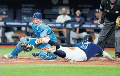  ?? MIKE EHRMANN GETTY IMAGES Tampa Bay’s Brandon Lowe escapes the tag of Jays catcher Zack Collins in the second inning at Tropicana Field. ??